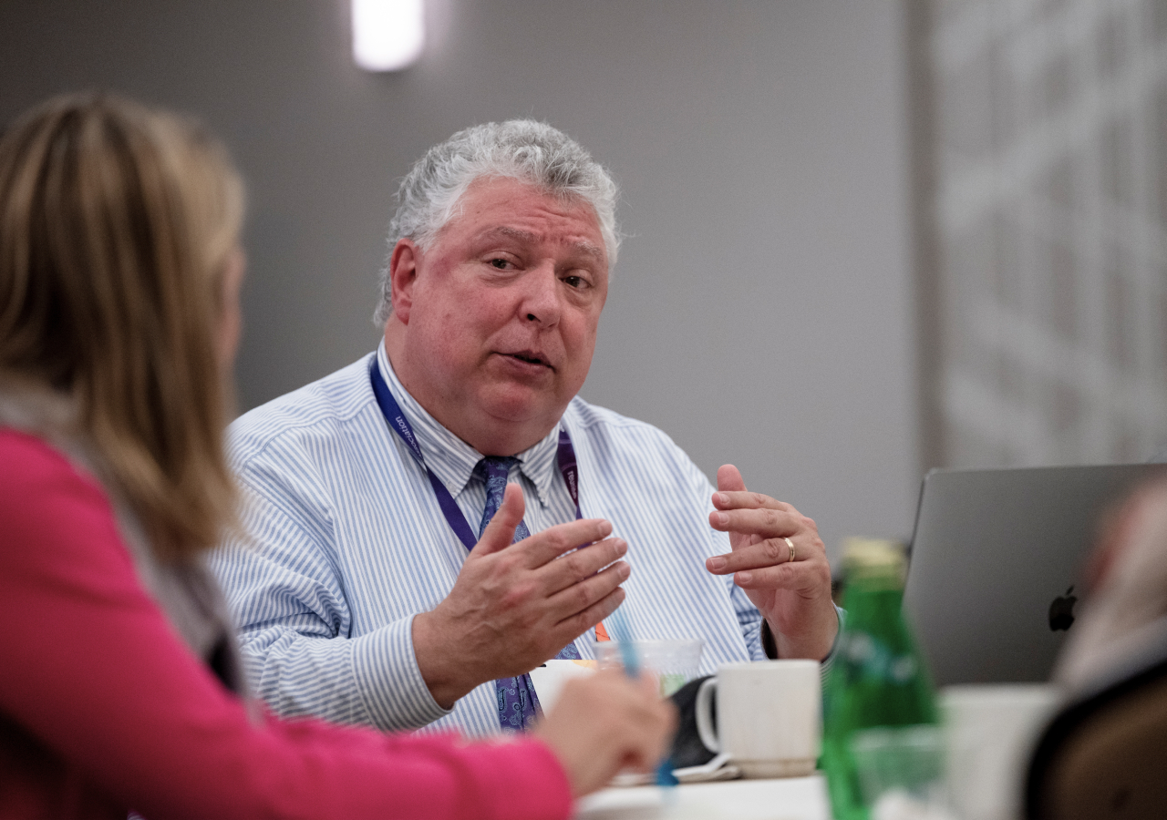 A man explaining a financial aid topic to a colleague during an EMA reception.